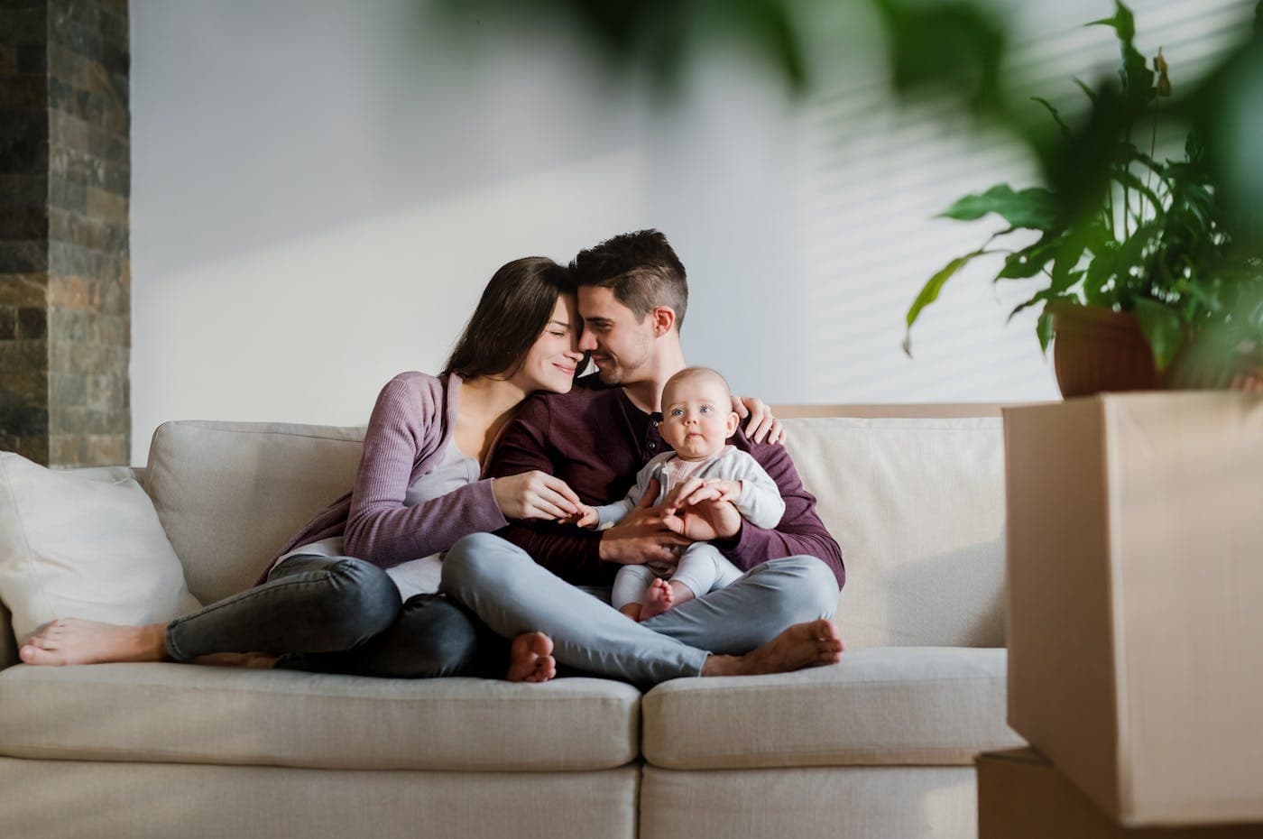 Un couple et son bébé sur un canapé, chez eux.