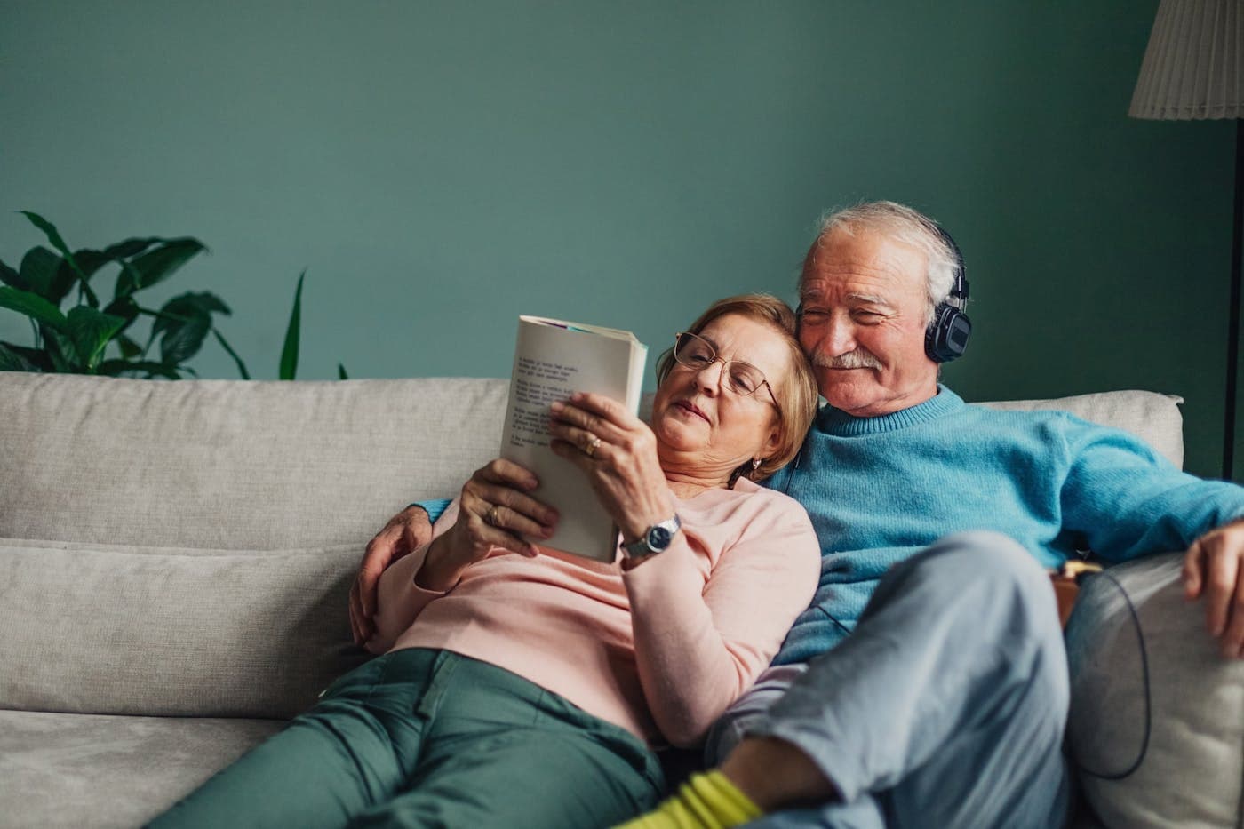 Un couple sur un canapé regarde une tablette, chez lui.