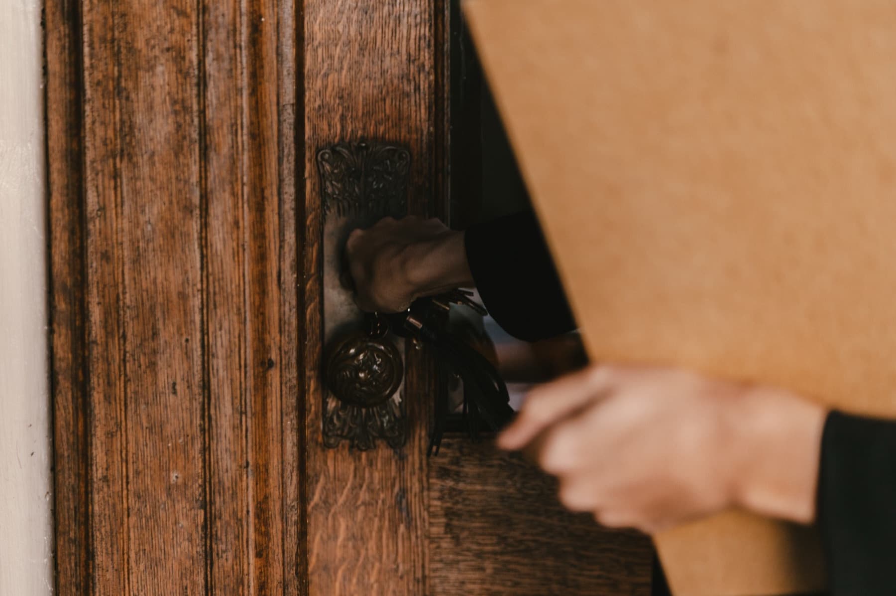 Une main tourne une clé dans la serrure d'une porte ancienne.